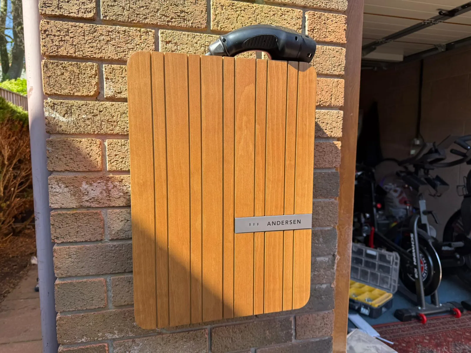 Andersen A2 EV charger with wood-effect finish mounted on a brick wall